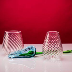 Glass calla lily flower next to saunter white and red glasses
